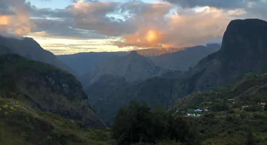 Al tramonto, le montagne della "diagonale des fous" si tingono di rosa. Un villaggio si intravede tra le valli verdi.