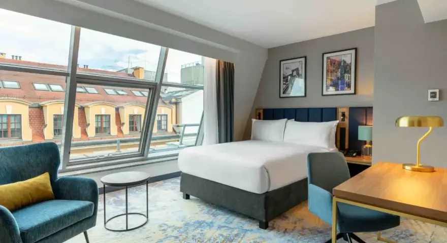 Nowoczesny pokój hotelowy z dużym oknem, łóżkiem i biurkiem. Czy trzeba być pełnoletnim, aby wynająć hotel? Tak, zazwyczaj tak.