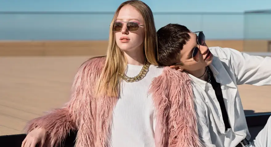 Chica con abrigo rosa peludo y collar dorado, apoyada en un chico con camisa blanca. Inspiración para como ser una chica aesthetic.