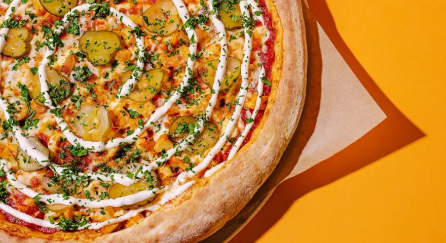 Apetyczna pizza z ogórkiem i sosem, idealna na szybki posiłek. Zastanawiasz się, ile kosztuje pizza we Włoszech?