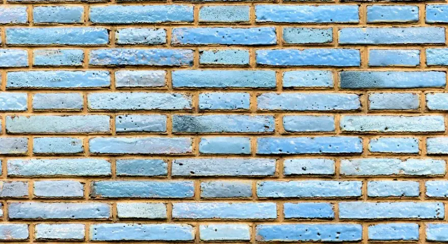 Textura de ladrillo visto pintado de azul claro, con juntas de mortero amarillentas.