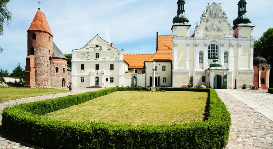 Kamienne kolumny w strzelnie otaczają trawnik przed barokowym kościołem i romańską wieżą.
