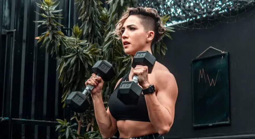 Kvinna utför hammer curls med hantlar. Stark och fokuserad, redo för nästa repetition.