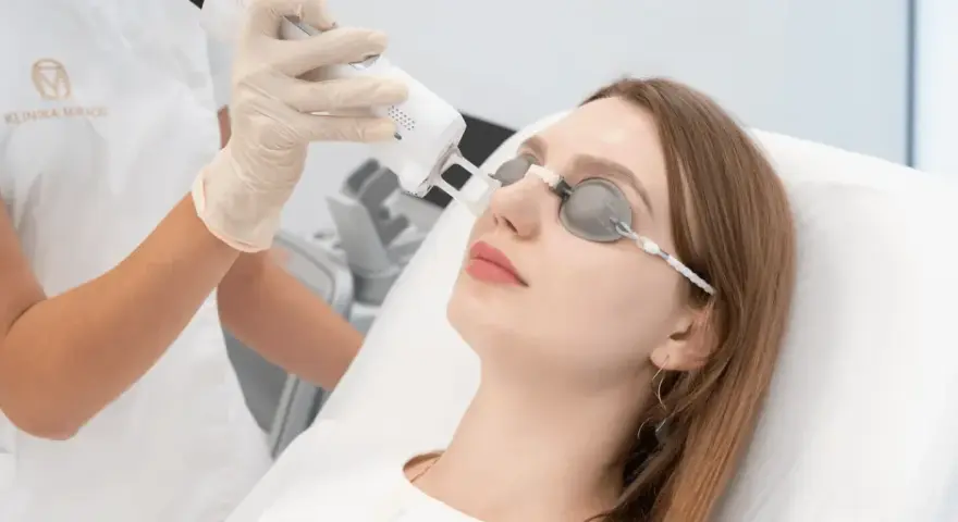 Fizykoterapia laserowa w klinice. Czas zabiegu laserem na twarz, pacjentka w okularach ochronnych.