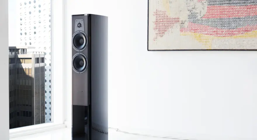 Elegancki głośnik Dynaudio Contour 30 w nowoczesnym wnętrzu, obok okna z widokiem na miasto.