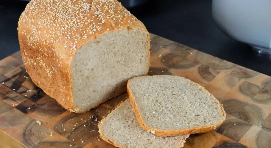 Frisch gebackenes sesam brot, mit zwei Scheiben auf einem Holzbrett.