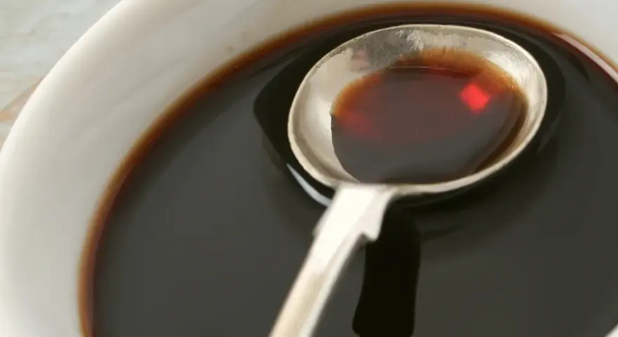 Łyżka z ciemnym płynem, idealnym do sosów i dressingów. Inspiracja do ocet balsamiczny przepisy.