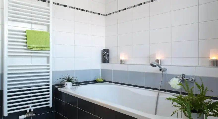 Salle de bain moderne avec baignoire, radiateur blanc et carrelage impeccable. Les joints de carrelage sont parfaits, donnant une finition propre.
