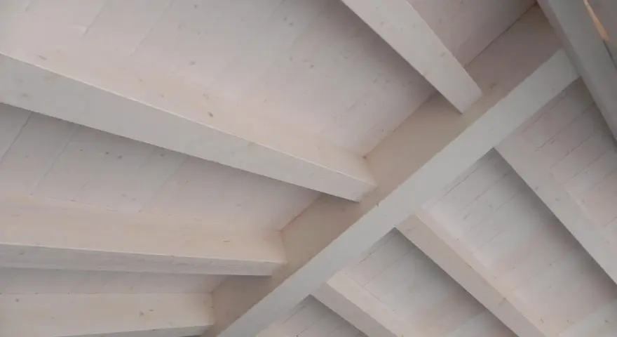 Techo de madera con vigas y tablones, acabado con veladura blanca que resalta la veta natural.