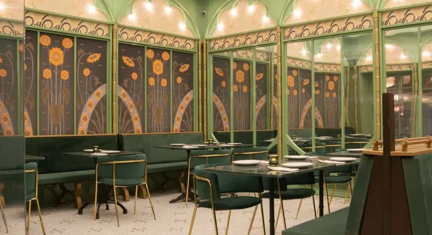 Elegante restaurante con mesas y sillas verdes, paredes decoradas con girasoles y detalles dorados. Un lugar perfecto para disfrutar de **frases restaurante** inspiradoras.