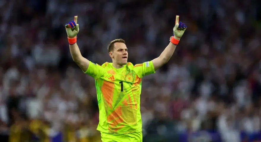 Manuel Neuer, bramkarz w neonowożółtej koszulce z numerem 1, świętuje zwycięstwo, unosząc ręce w geście triumfu.