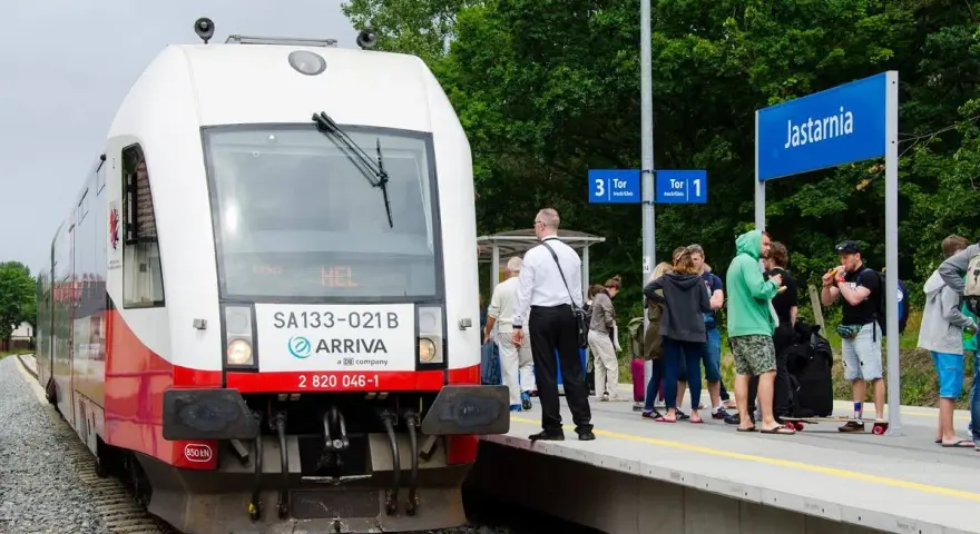 Pociąg Arriva z napisem HEL czeka na pasażerów w Jastarni. Ludzie z bagażami stoją na peronie, gotowi do podróży z Helu do Gdańska.