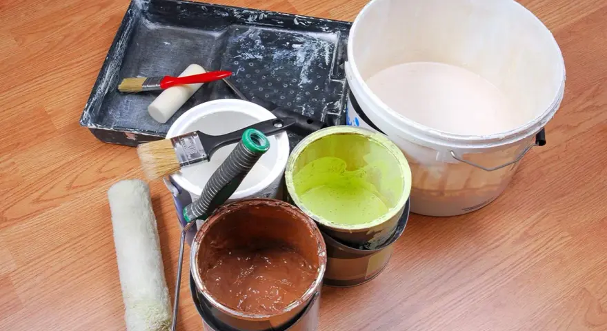 Attrezzi per pittura e barattoli di vernice avanzata, pronti per essere conservati.