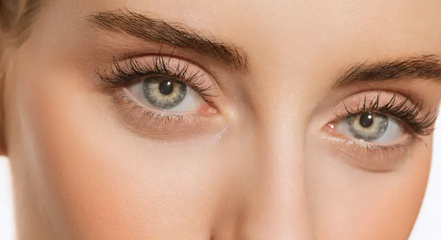 Maquillage subtil pour paupières tombantes, rehaussé par le regard intense derrière des lunettes imaginaires.