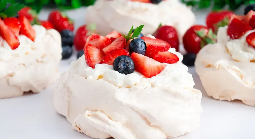 Klasyczna Pavlova z owocami i kremem lub małe beziki z kremem. Pyszne, lekkie desery.