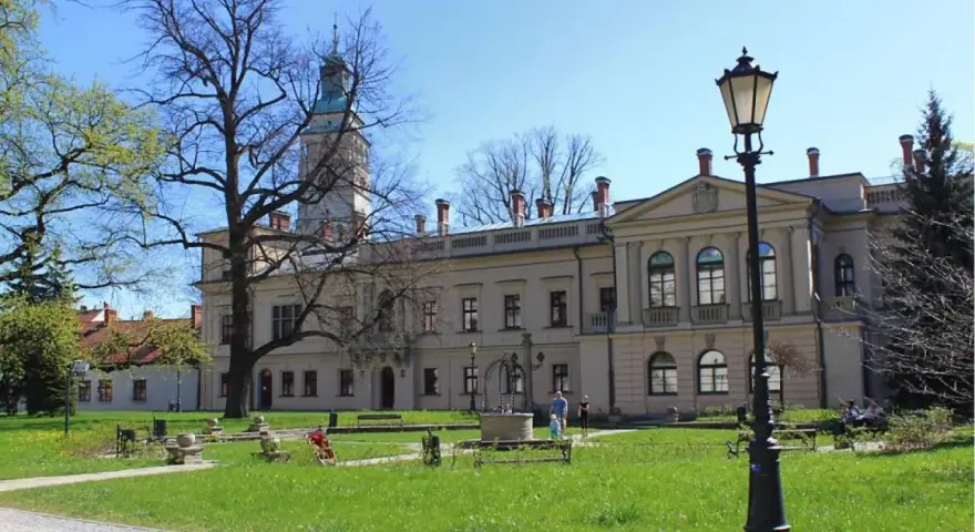 Zamek w Żywcu, z wieżą i dziedzińcem, otoczony zielenią i drzewami.