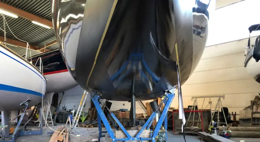 Schwarzer Rumpf einer Yacht im Trockendock, bereit, das Antifouling zu erneuern.