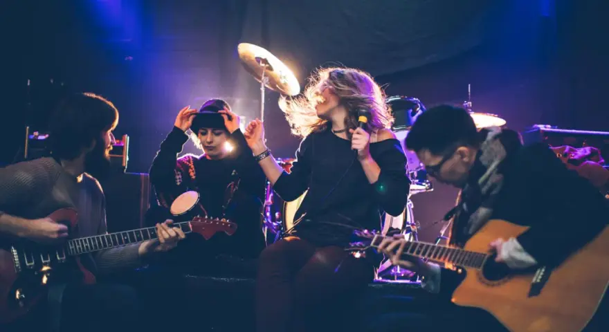 Band bei der Probe, die eine **cover musik** spielt. Sängerin mit Mikrofon, Gitarristen und Schlagzeuger im Scheinwerferlicht.
