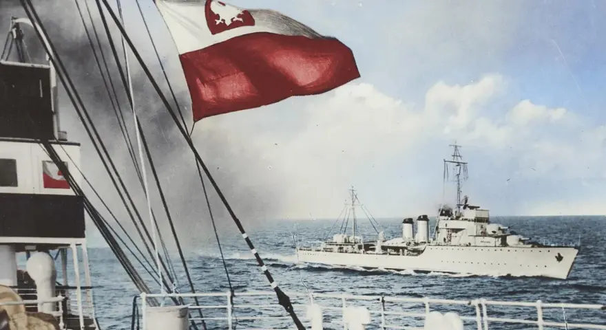 ORP Wicher płynie po wzburzonym morzu. Na pierwszym planie widać fragment statku i polską flagę.