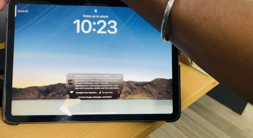 Tablet z włączonym ekranem blokady, widoczny napis "Touch ID" i godzina 10:23. Na ekranie wyświetla się powiadomienie z kodem weryfikacyjnym.