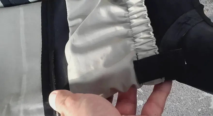 Hand hält ein Hosenbein mit elastischem Bund und Klettverschluss. Vielleicht ein Flicken für die wathose?