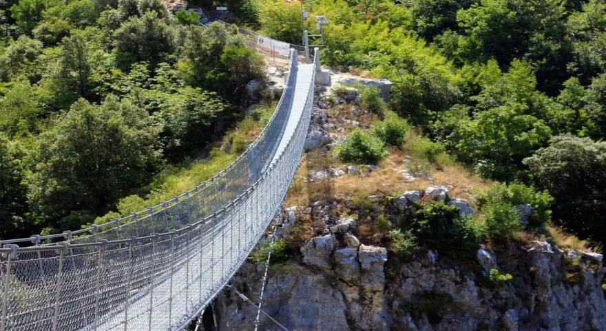 Un lungo ponte tibetano si snoda tra rocce e vegetazione lussureggiante, offrendo un'avventura mozzafiato nei dintorni di Salerno.