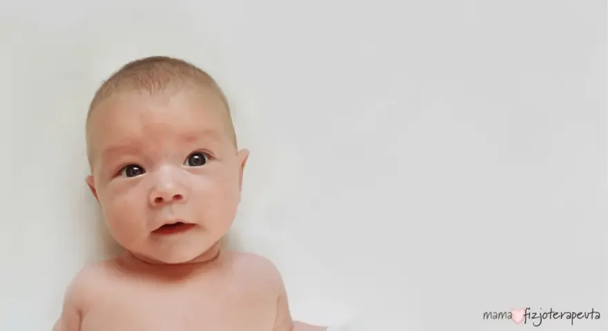 Urocze niemowlę z zaciekawieniem patrzy w obiektyw. Może to początek drogi do pokonania kręcz szyi.