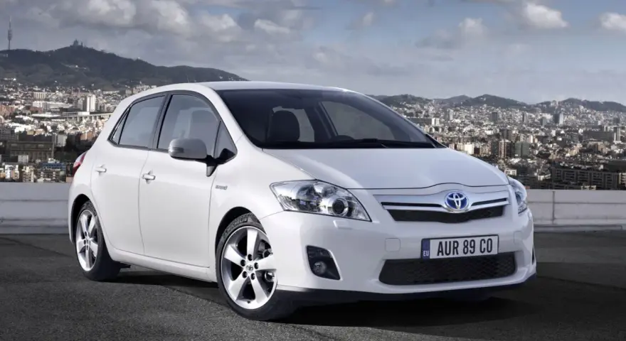 Biała Toyota Auris hybryda na tle miasta. Czy warto zainwestować w ten model?