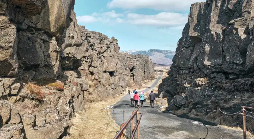 Spacerem przez szczelinę tektoniczną w parku narodowym Þingvellir. Grupa turystów podziwia surowe piękno islandzkiej przyrody.