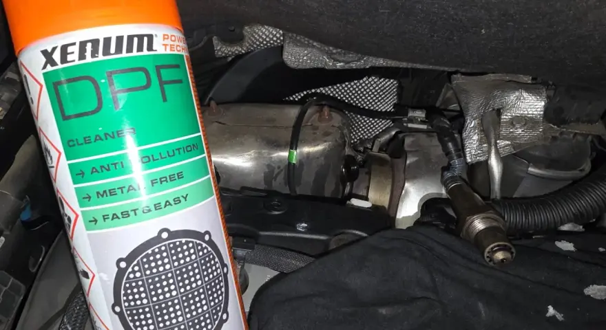 Bouteille de nettoyant FAP Xenum à côté d'un capteur et de pièces de moteur.