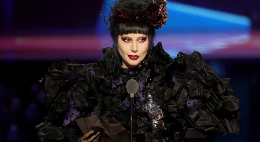 Lady Gaga w Polsce, w czarnej, falbaniastej sukni z fioletowymi wstawkami, odbiera nagrodę.