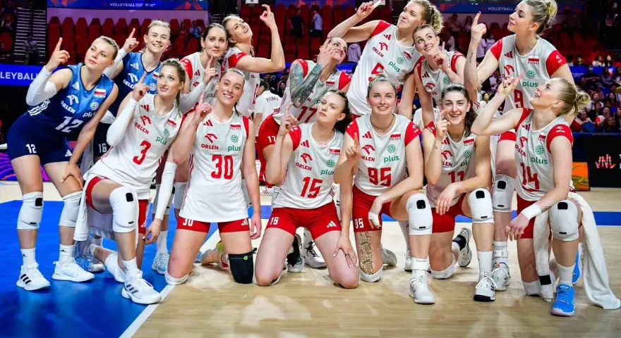 Siatkarki reprezentacji Polski w siatkówce, uśmiechnięte, pozują do zdjęcia, wskazując palcami w górę.