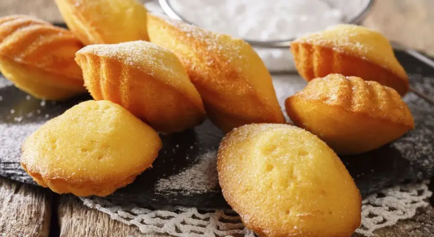 Des madeleines dorées, saupoudrées de sucre glace, prêtes à être dégustées. Une invitation à la recette madeleine parfaite.