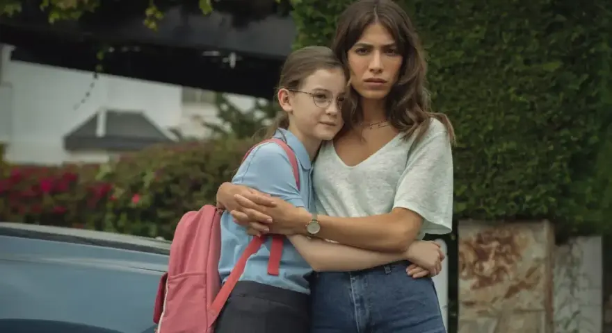 Erin Carter abbraccia una bambina con uno zaino rosa. La donna sembra preoccupata, la bambina protetta.