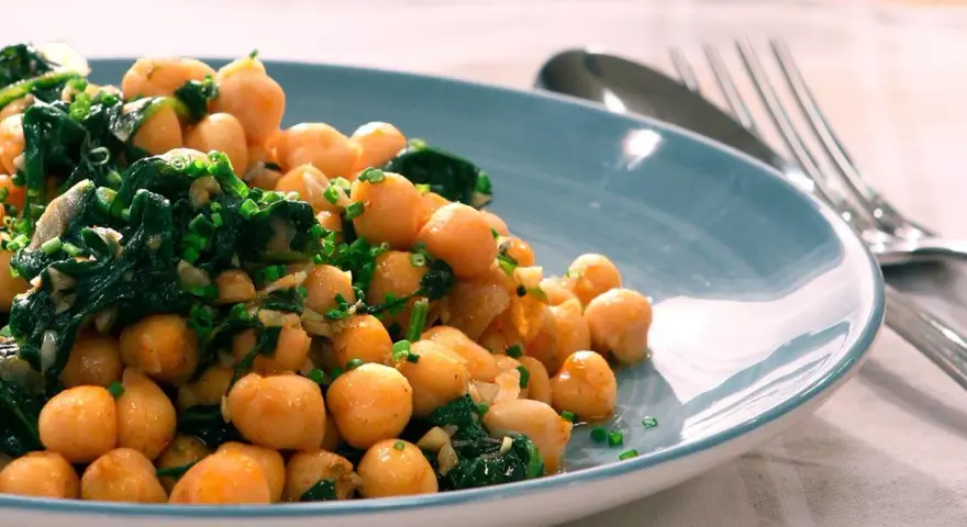 Garbanzos salteados con espinacas y ajo, una de las muchas recetas con garbanzos de bote, servidos en plato azul.