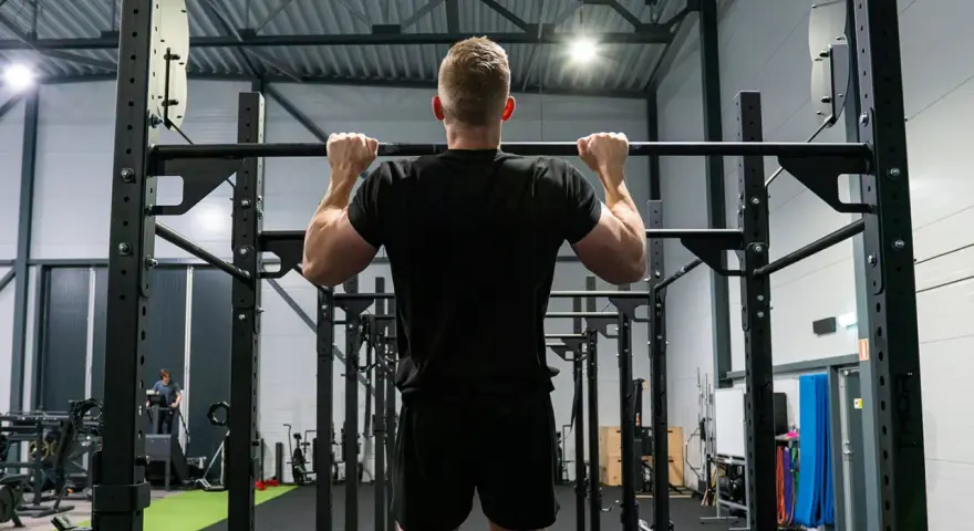 Man tränar pull ups i ett modernt gym.