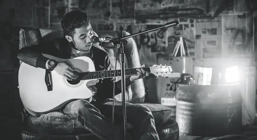Młody muzyk gra na gitarze, tworząc największe hity bluesowe w surowym, industrialnym wnętrzu.