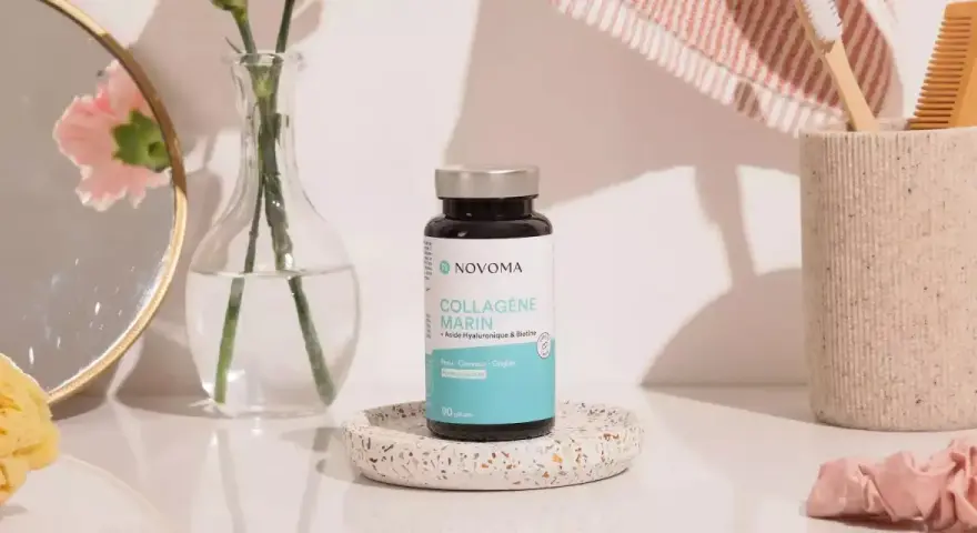 Flacon de cure de collagène marin Novoma, posé sur un plateau décoratif, près d'un miroir, d'une fleur et d'une brosse à dents.