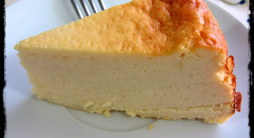 Una rebanada de tarta de queso light, con su dorada superficie y cremosa textura, lista para disfrutar.