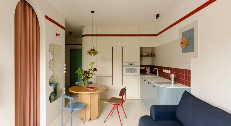 Un angolo di casa moderna con richiami alle case tipiche italiane: un tavolo rotondo, sedie colorate e una cucina funzionale.