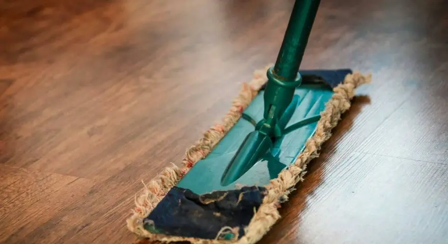 Mopa limpiando un suelo de parquet. Descubre remedios caseros para reparar parquet y mantenerlo como nuevo.