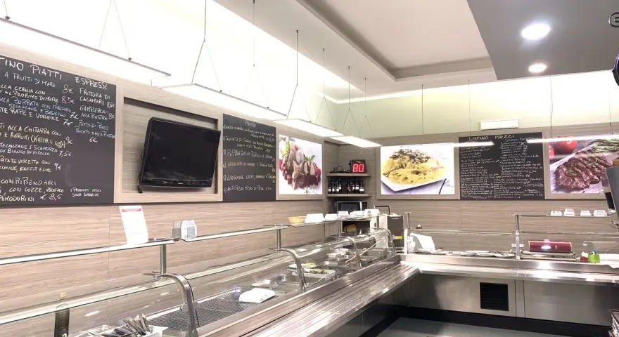 Interior of a restaurant with a display counter, menu boards, and food images.