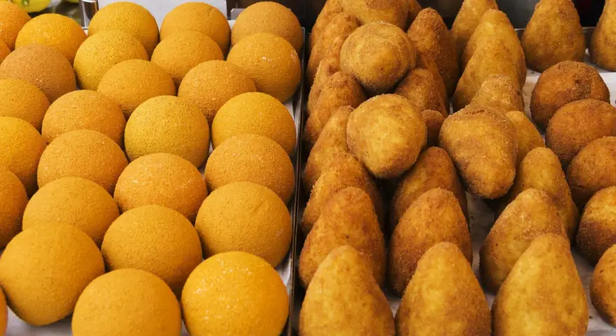 Arancini e arancine dorati, pronti per essere gustati. Un tripudio di sapori siciliani.