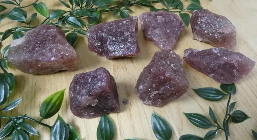 Gruppo di quarzo fragola grezzo su fondo di legno. Le sue proprietà sono note per favorire l'amore e la guarigione emotiva.