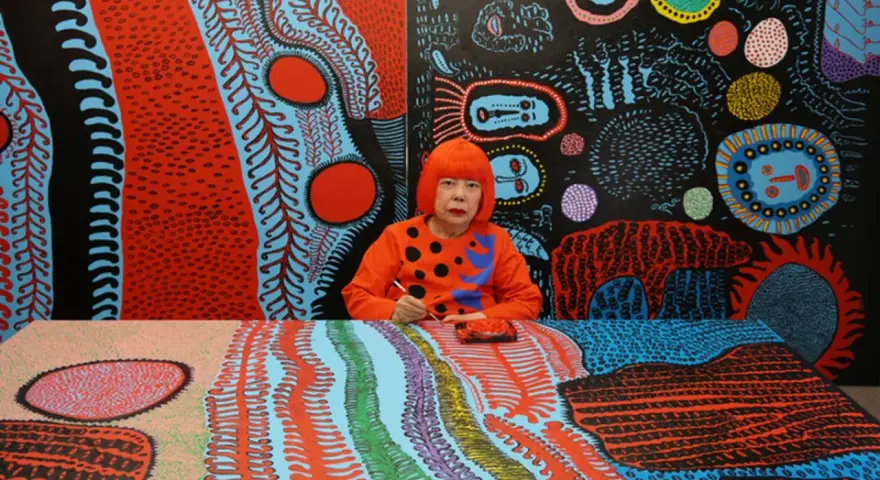 Yayoi Kusama jeune, entourée de ses œuvres psychédéliques vibrantes, peignant avec une concentration intense.