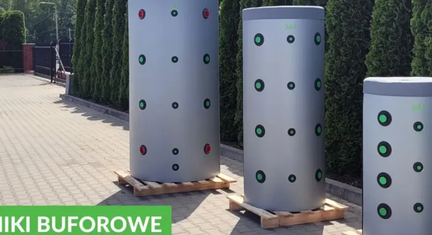 Trzy cylindryczne bufory 1000l wymiary, stojące na paletach przed żywopłotem. Zielone i czerwone kółka na szarych zbiornikach.