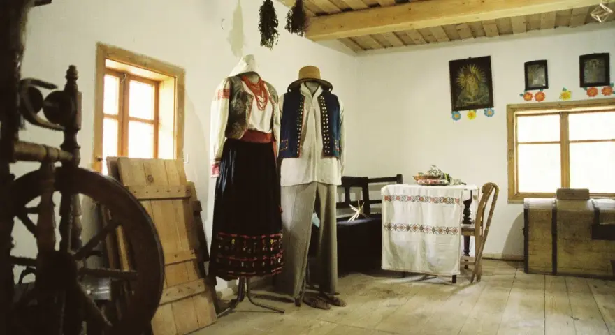 Tradycyjne stroje ludowe, kołowrotek i obrazy religijne tworzą klimat dawnej wsi. To żywa hel historia.