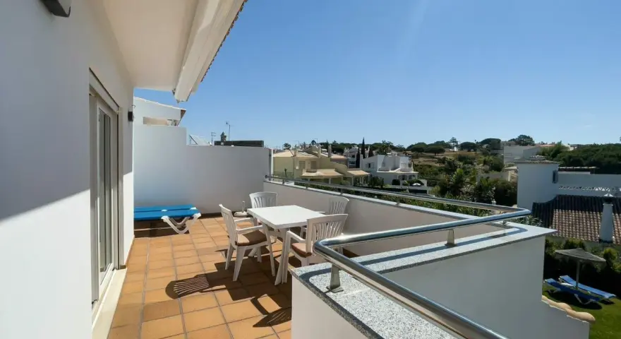 Słoneczny balkon z meblami i widokiem na domki. Idealne miejsce na poranną kawę i planowanie dnia.
