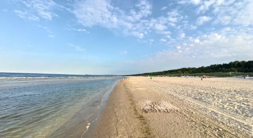 Sonniger Karlshagen Strand mit sanften Wellen und weitem Sand. Ein perfekter Ort für entspannte Tage am Meer.
