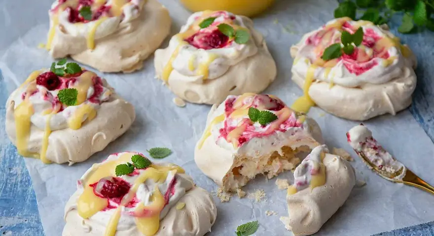 Små pavlovakakor med grädde, hallon och citronsås. En perfekt liten dessert!
